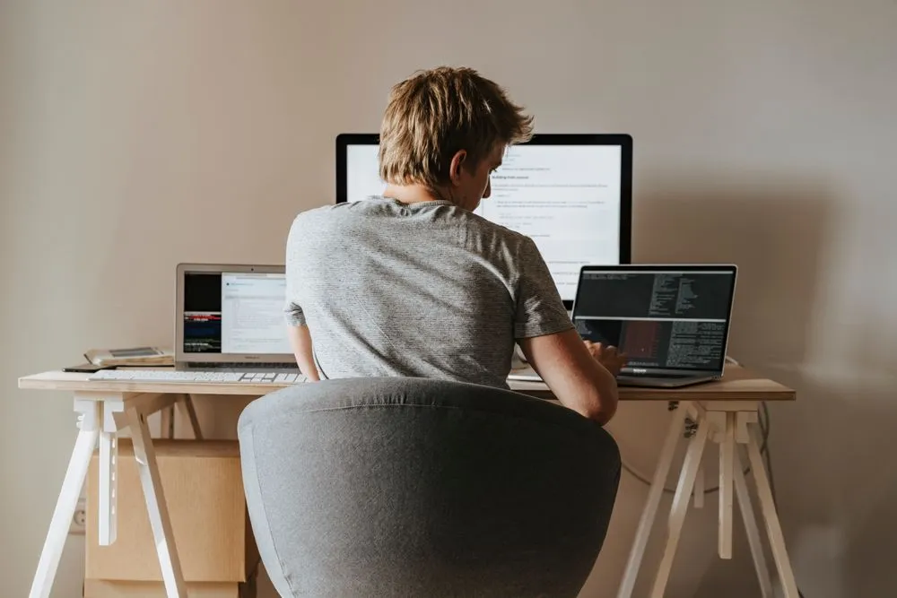 A developer works at several screens in his home office.
